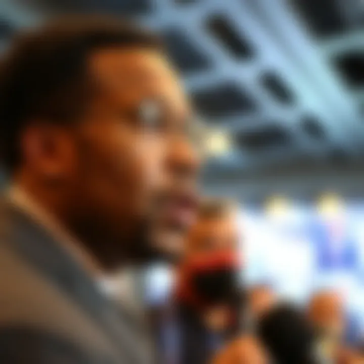 Malik Washington at a press conference, addressing the crowd with a serious expression, surrounded by reporters and cameras